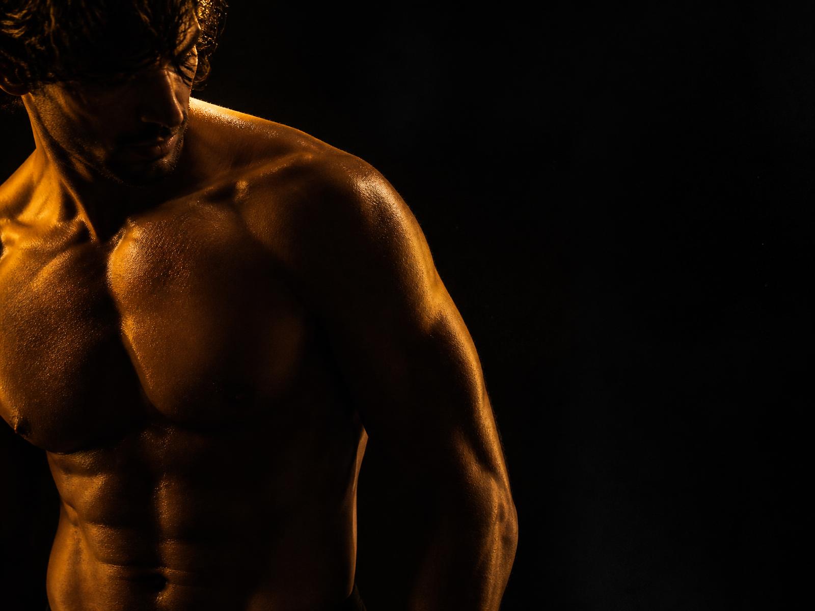 Athletic man lit by a single amber rim light